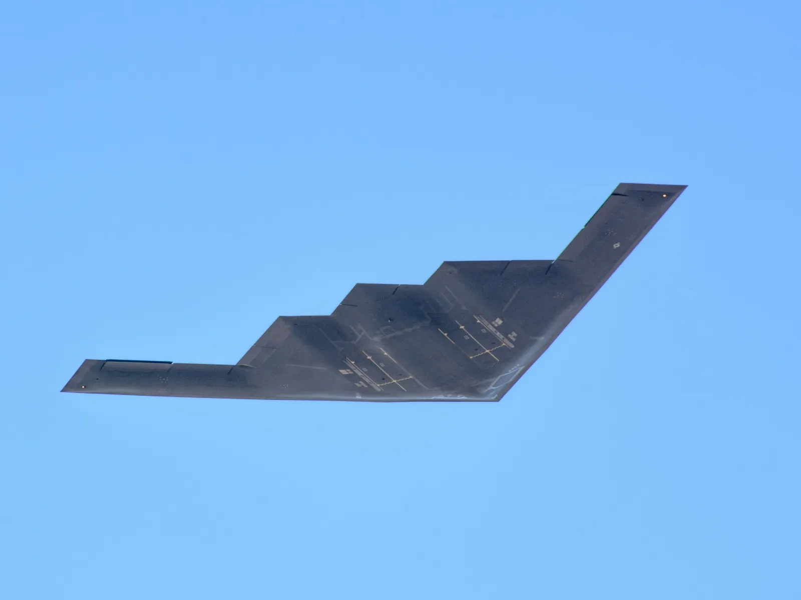 Naval ship firing its large caliber deck gun over calm ocean waters during daytime