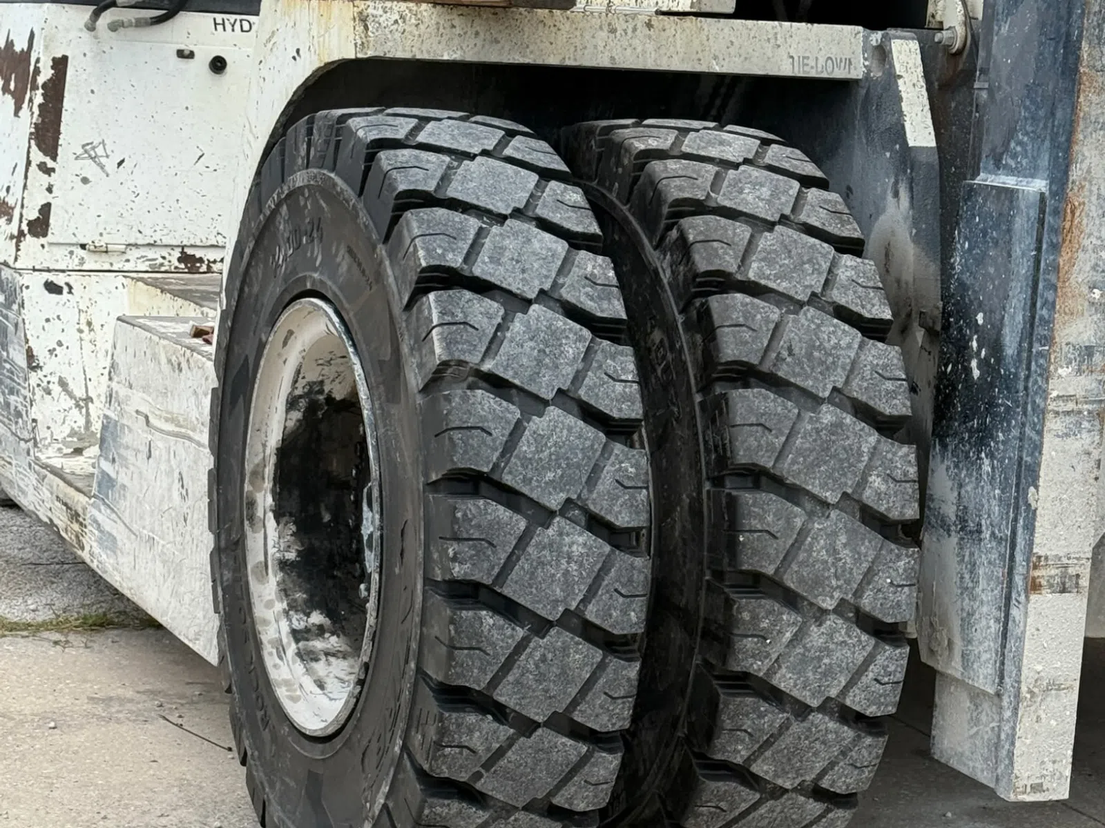 Close-up of dual heavy-duty tires on an industrial forklift with rugged tread patterns on concrete ground.