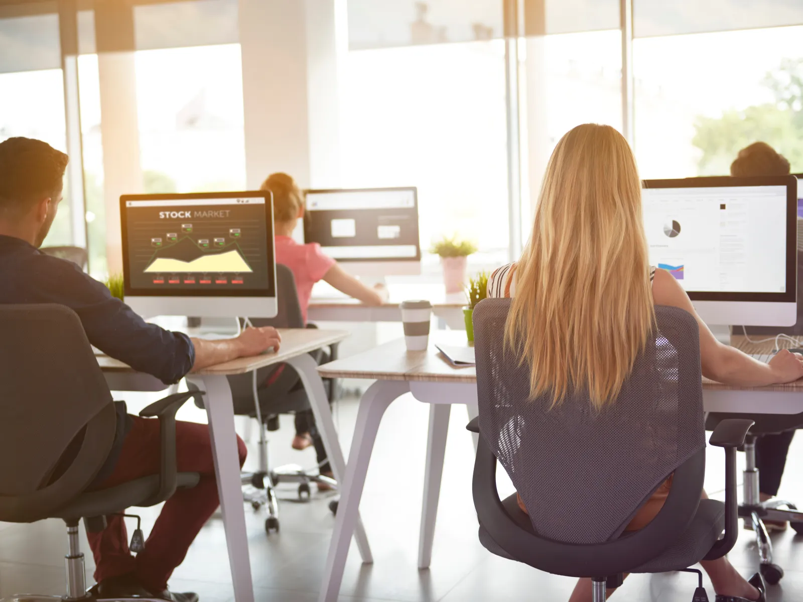 Group of professionals working at computers in a modern office setting, collaborating on digital projects.