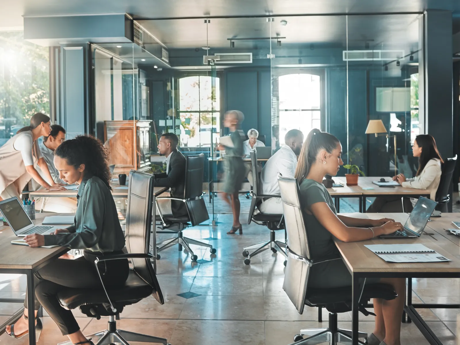 Modern office with diverse professionals working on laptops and collaborating in a bright open workspace