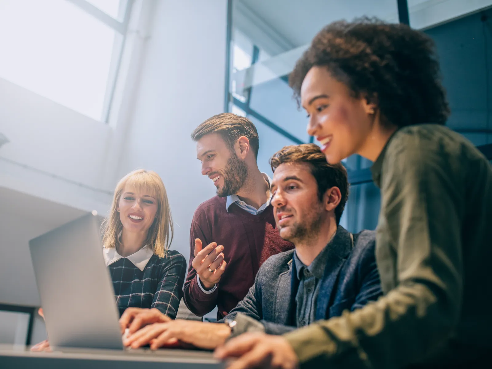 Group of professionals working at computers in a modern office setting, collaborating on digital projects.