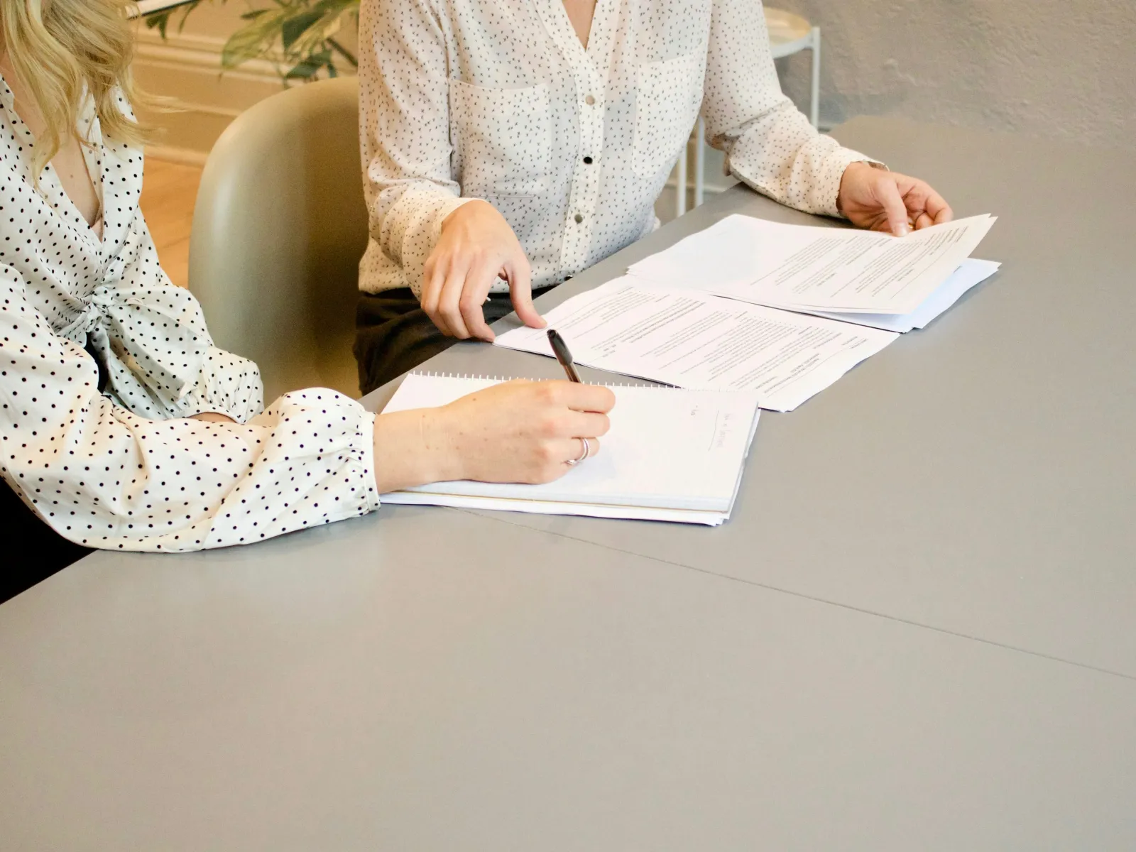 Close-up of hands reviewing documents on a table during a business meeting.
