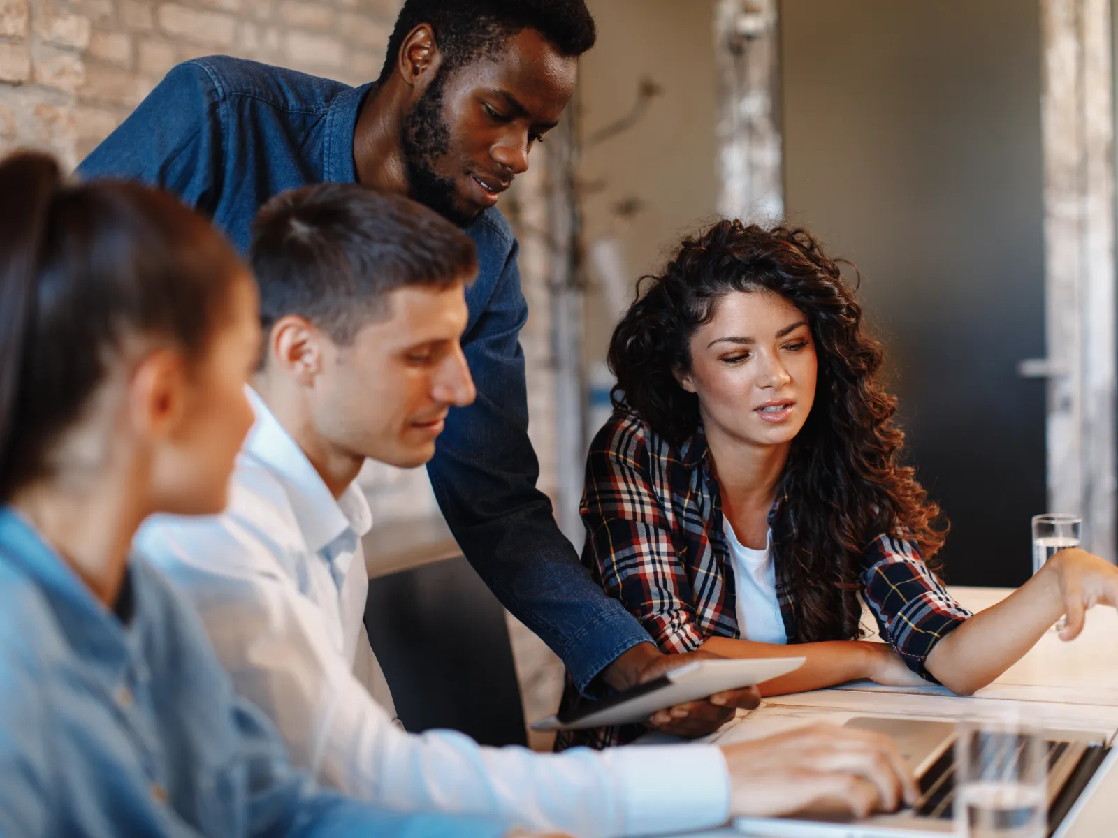 Modern office with diverse professionals working on laptops and collaborating in a bright open workspace