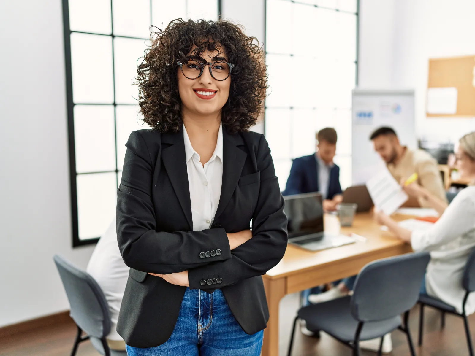 Smiling woman on a phone at her desk, engaged in a professional conversation in an office setting.