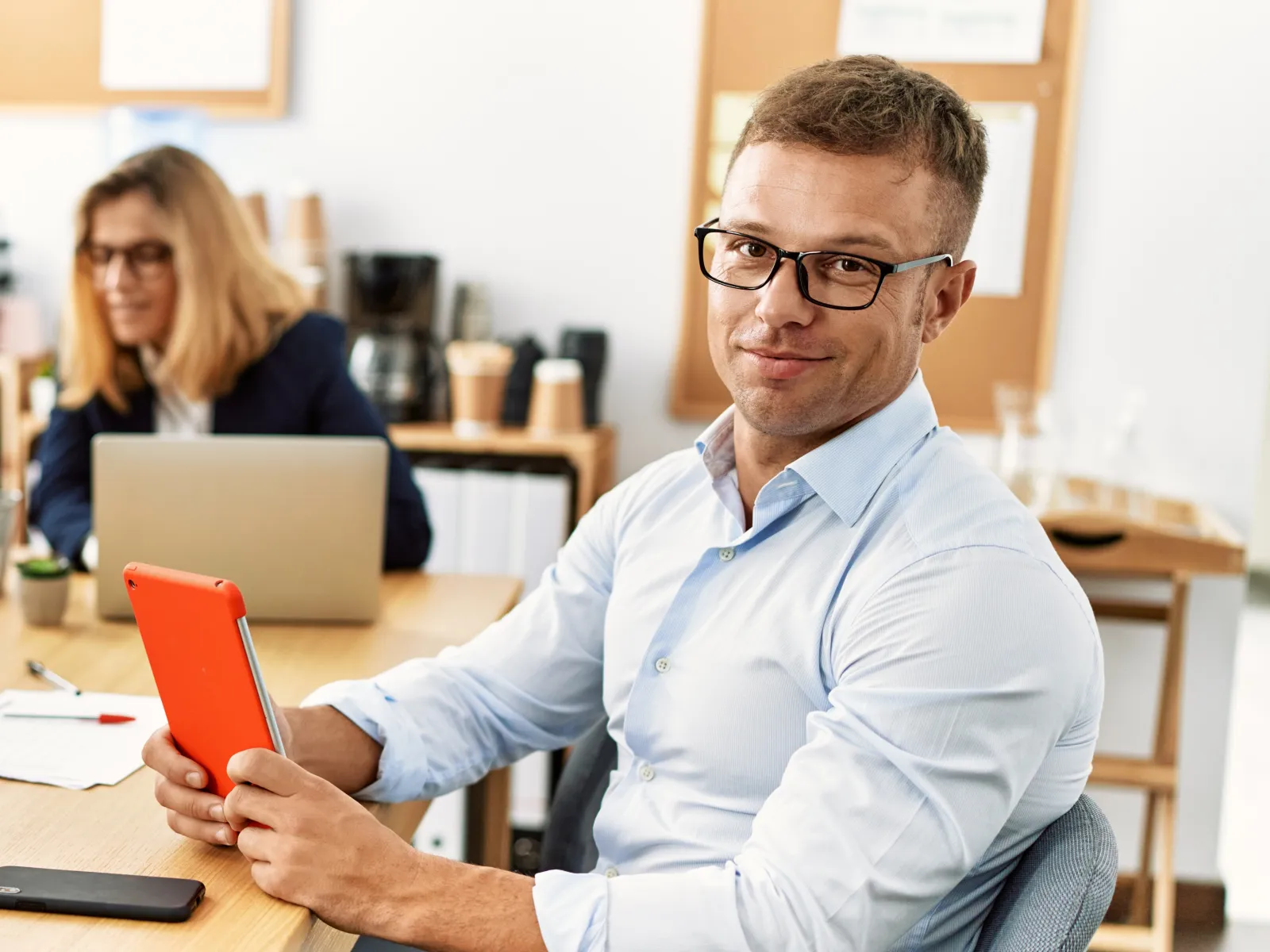 Group of professionals collaborating around a table with laptops and tablets in a modern office environment.