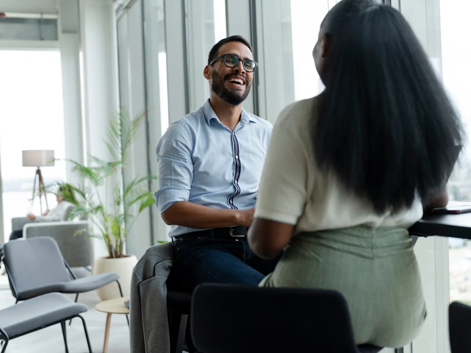 Two professionals enjoying a friendly conversation in a modern office space with natural light.