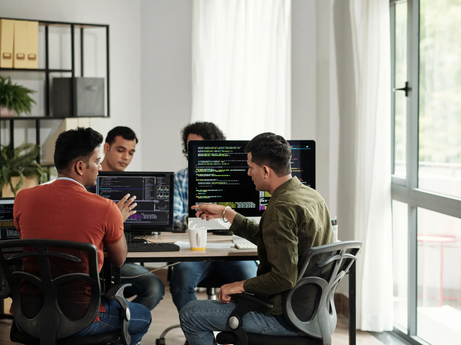 Team of developers collaborating on coding projects in a modern office environment.