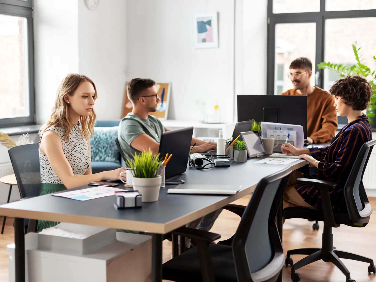 Group of professionals working at computers in a modern office setting, collaborating on digital projects.