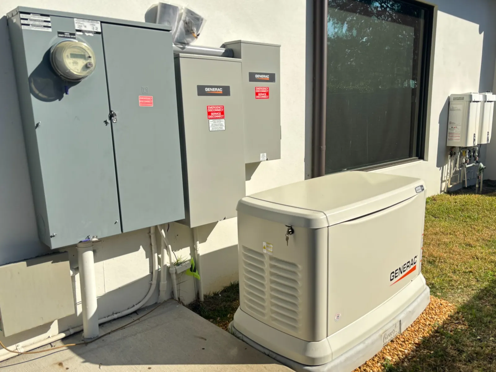Generac standby generator system and electrical panels mounted outside a house on a sunny day.