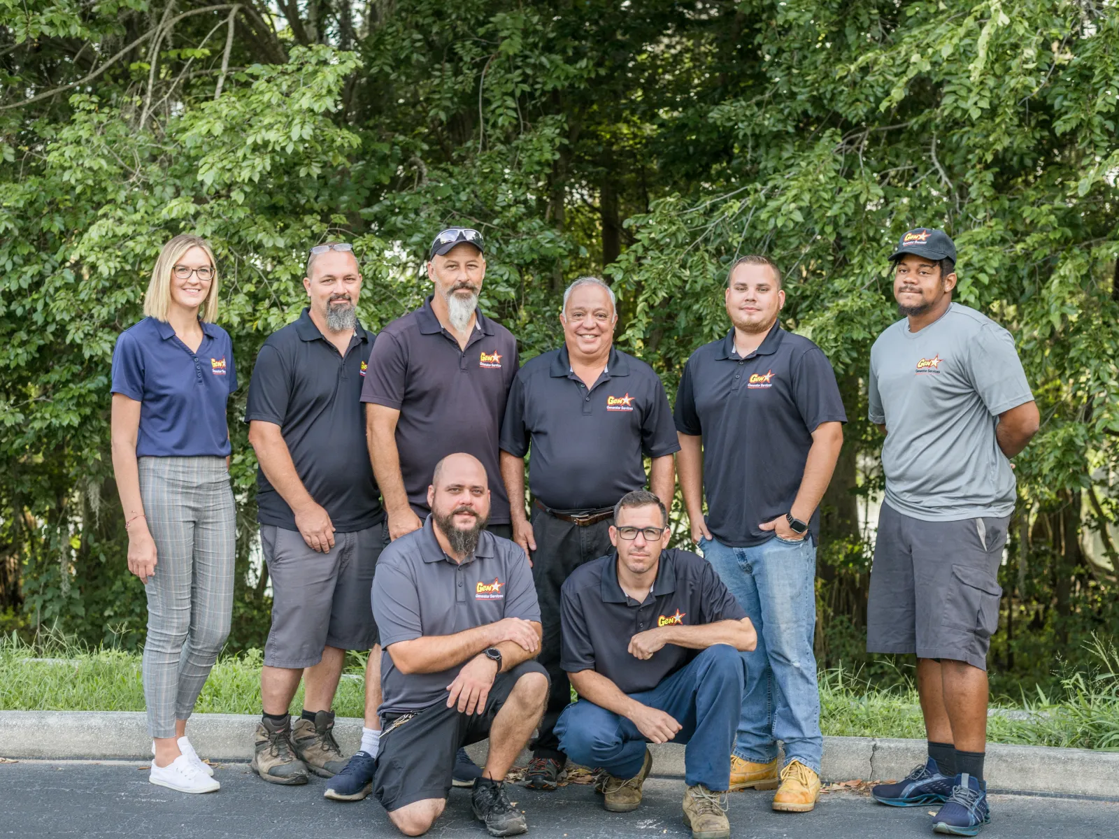 A skilled team in uniforms poses outdoors, surrounded by greenery, showcasing teamwork and professionalism.