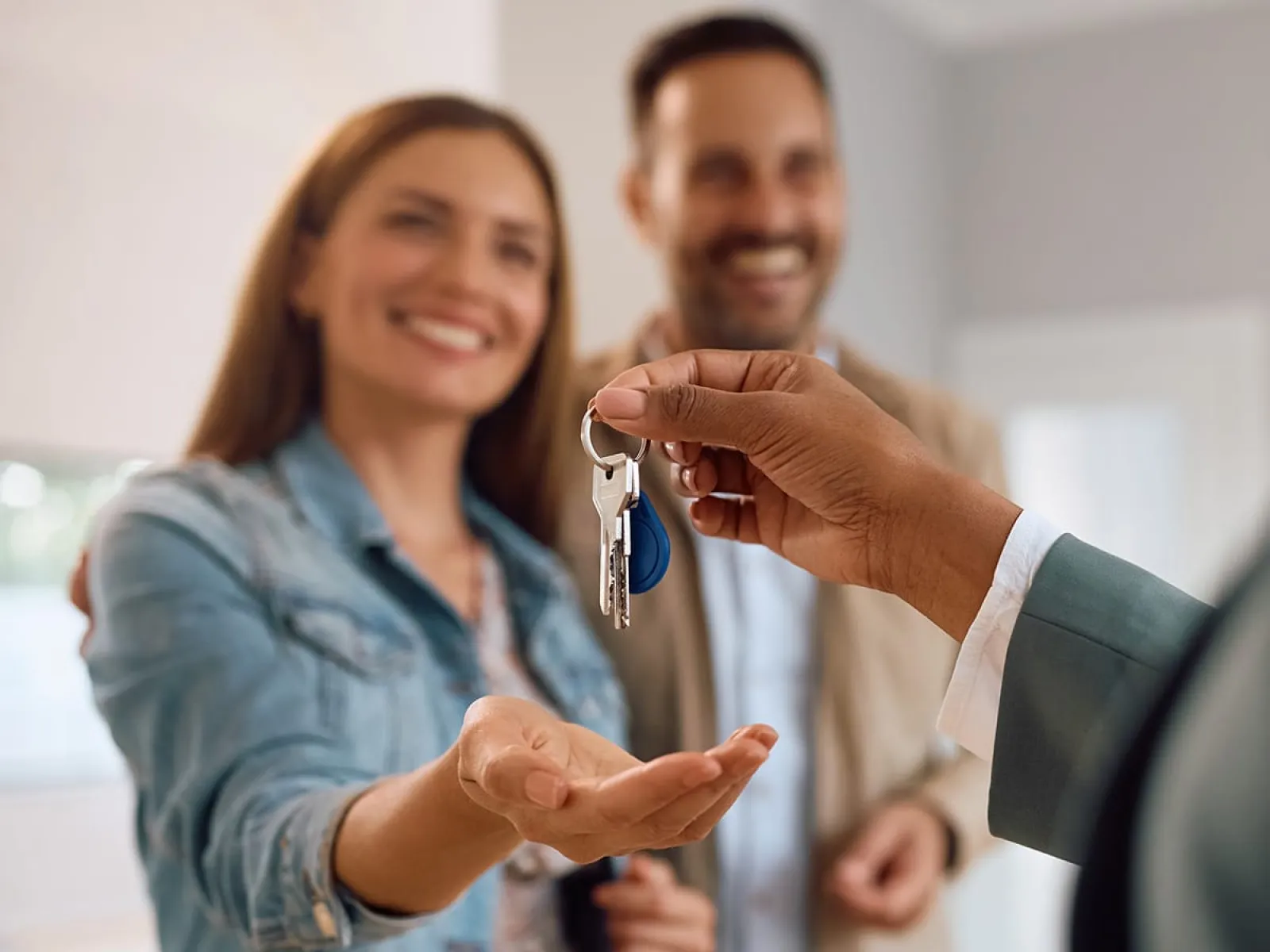 Real estate agent handing keys to happy couple in new home