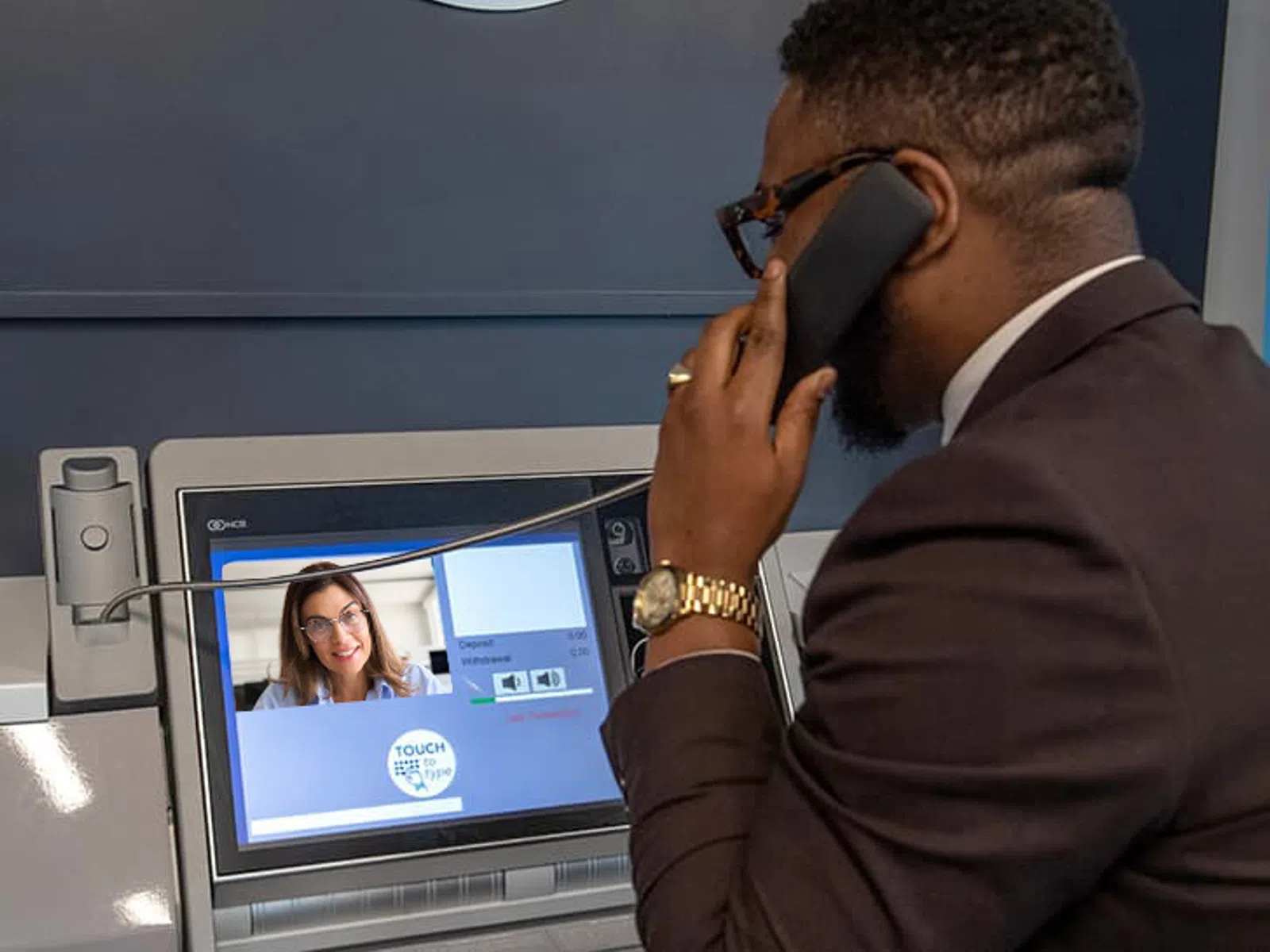Man using video banking service at ATM with headset and touchscreen interface for remote assistance