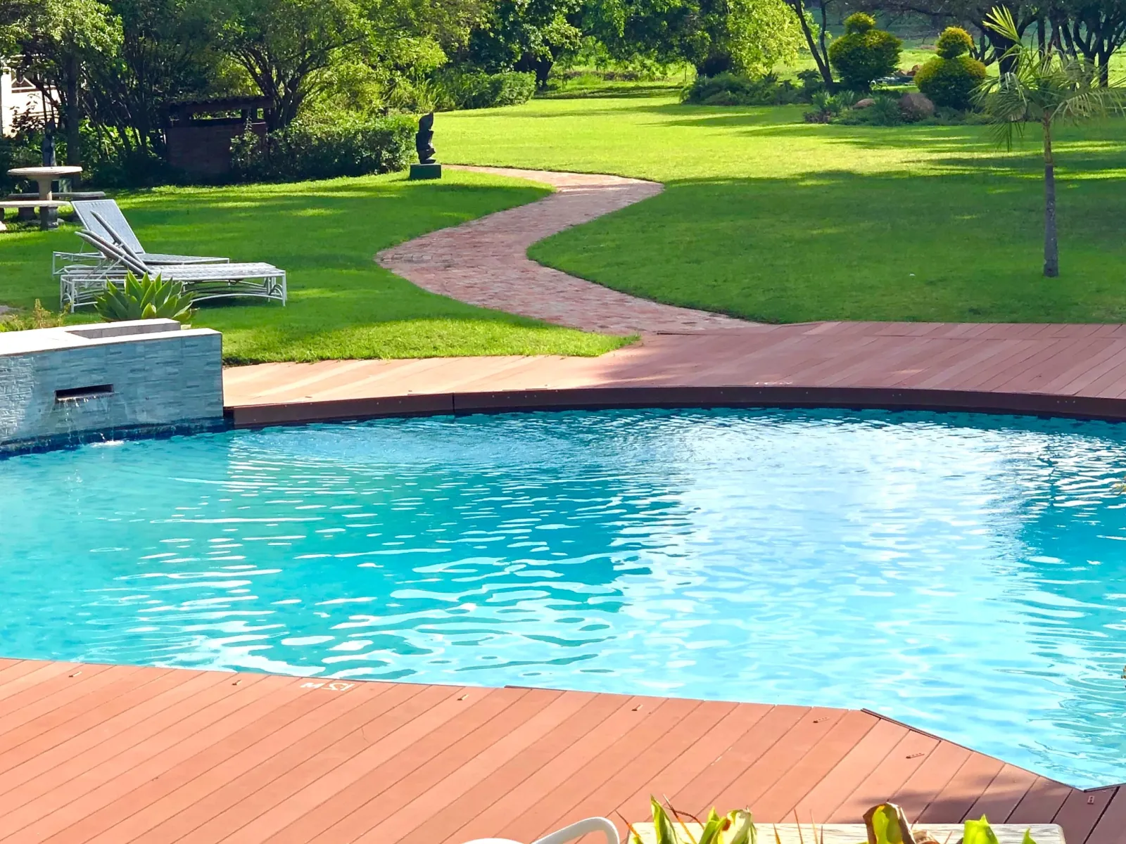 a pool with a grass lawn and trees in the background