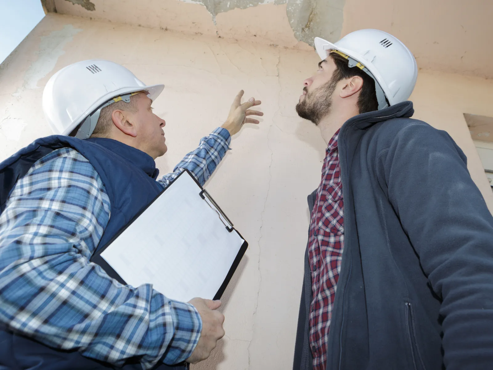 men wearing hard hats looking at a laptop