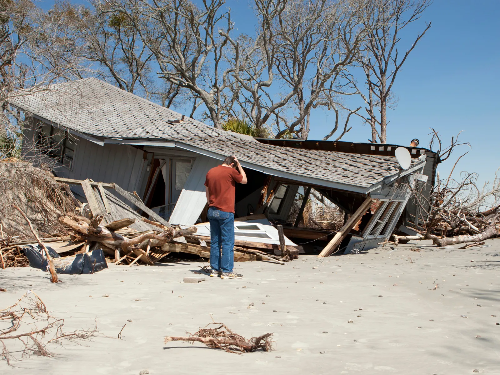 a person standing next to a house that is falling apart