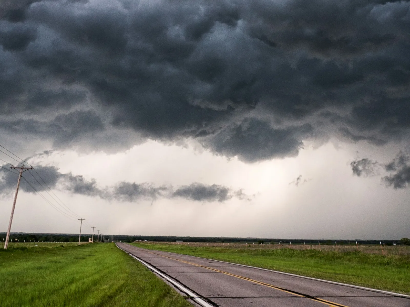 a road with grass and clouds above