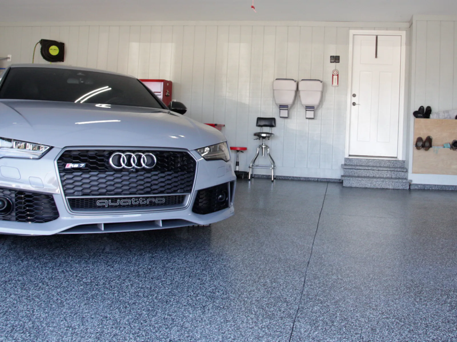 Silver Audi RS7 parked inside a clean, organized garage with epoxy flooring and wall-mounted storage.