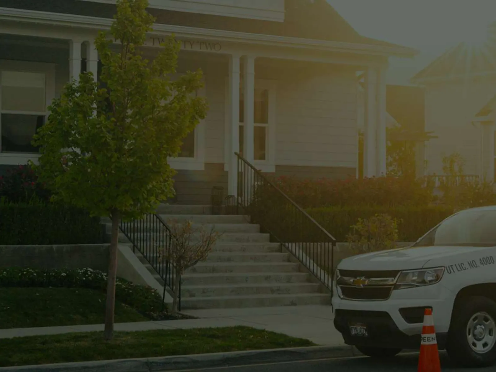 White and green Greenix company truck parked in front of residential houses in the evening.