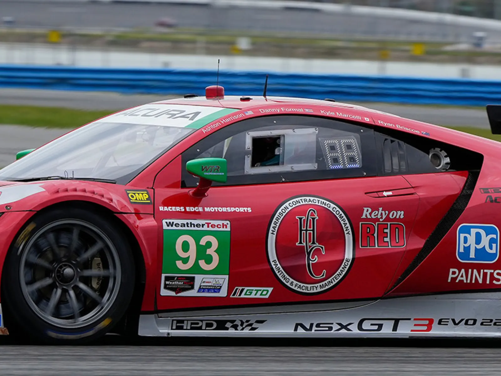 Red Acura NSX GT3 racing car number 93 on a race track with sponsor logos and aerodynamic features