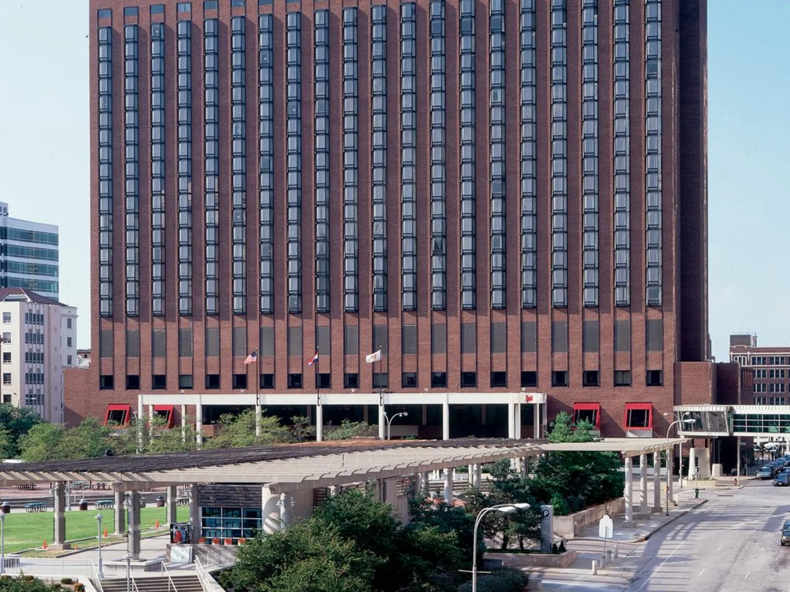 Marriott hotel building with multiple windows overlooking a busy city street and a pedestrian walkway above.
