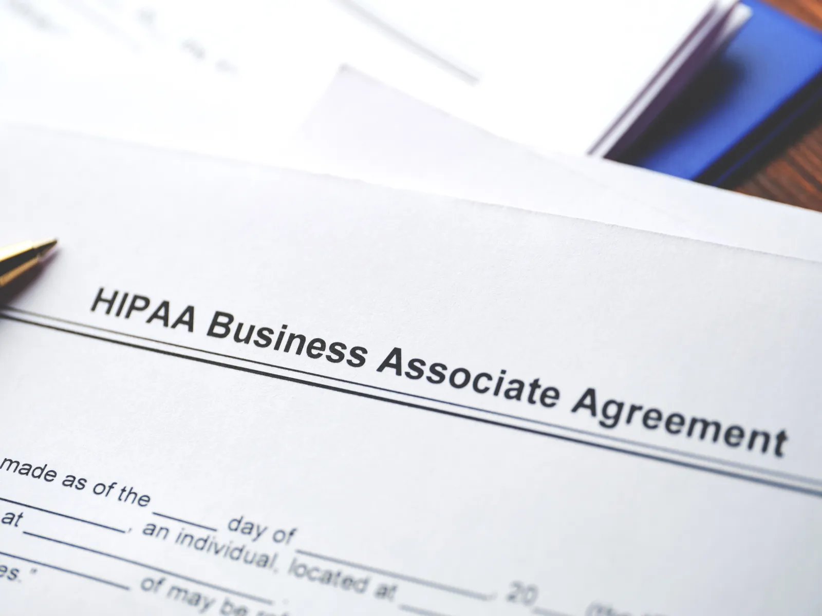 Close-up of a HIPAA Business Associate Agreement document with pen and mobile phone in background.