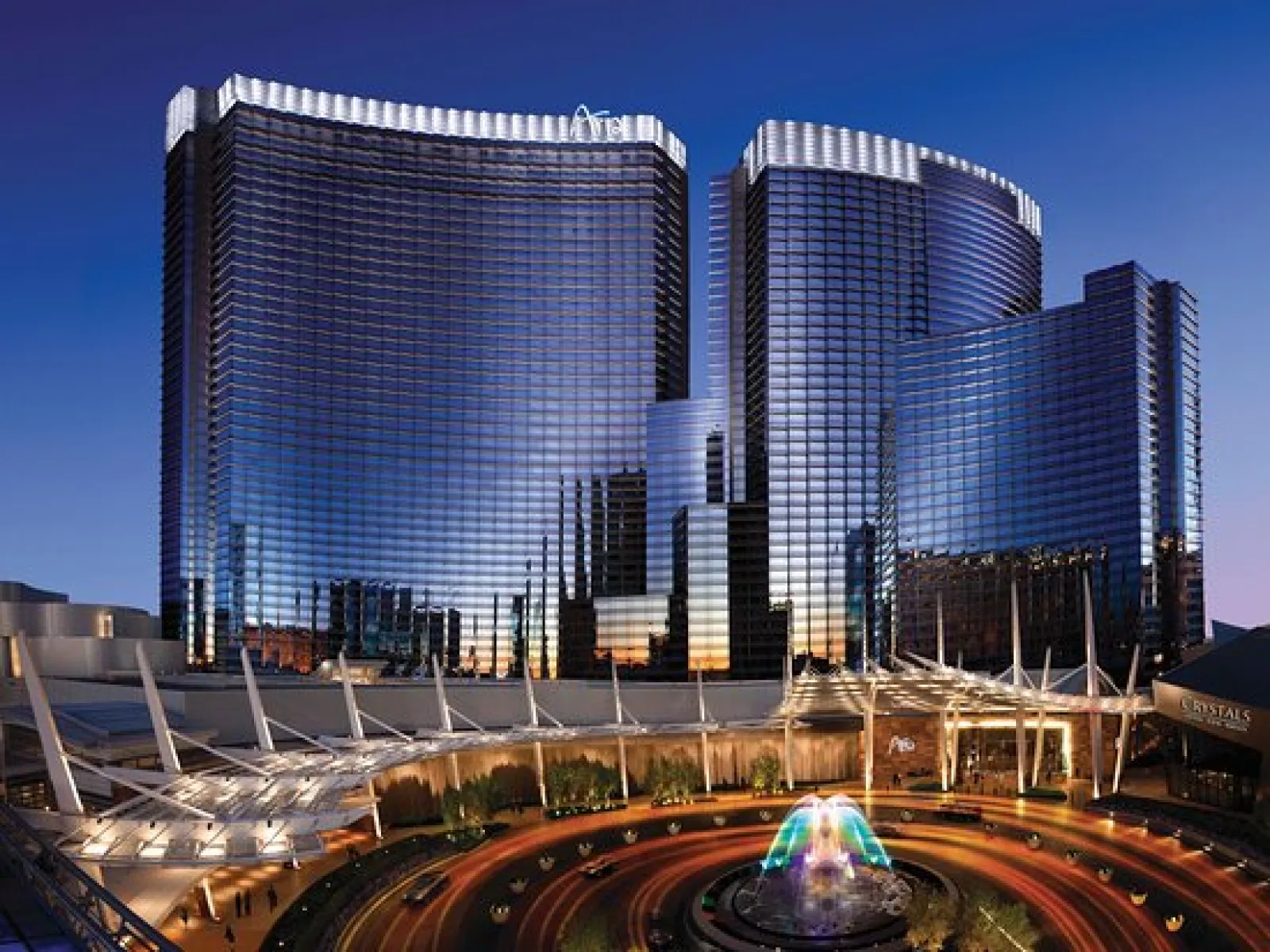 Luxurious hotel towers reflecting sunset in Las Vegas, featuring modern architecture and vibrant fountains.