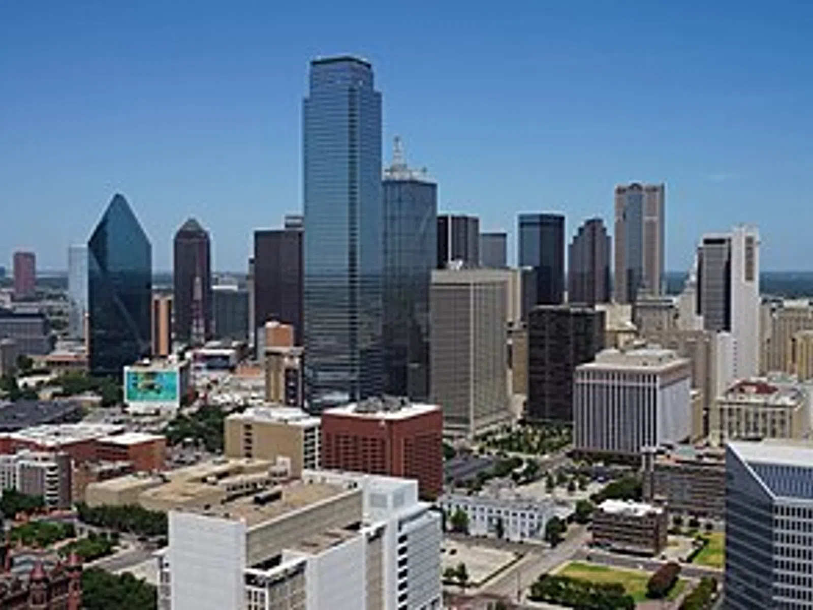 A clear blue sky over the Dallas Texas skyline with tall modern skyscrapers and city buildings in daylight.