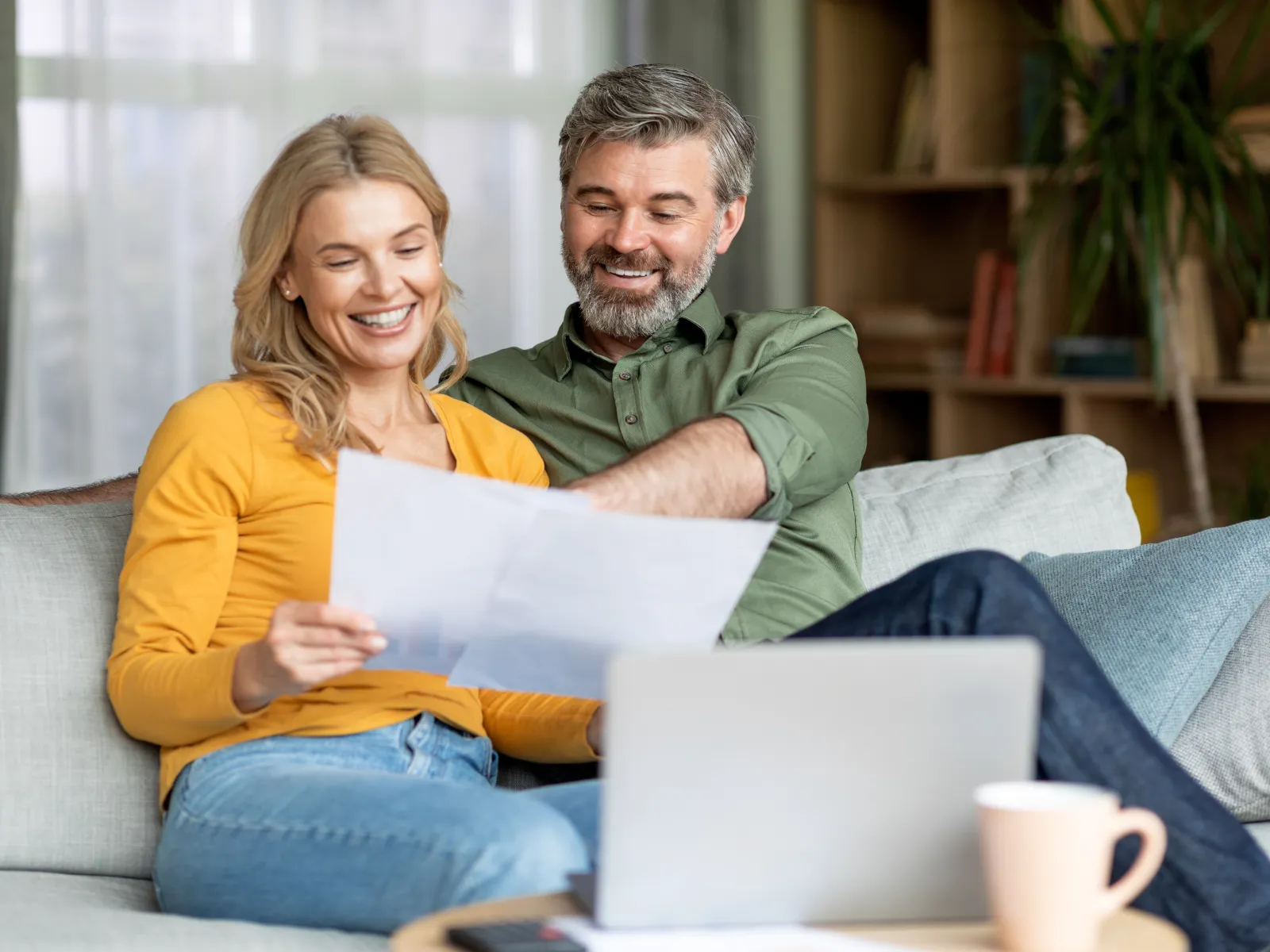 a man and a woman sitting on a couch looking at a laptop