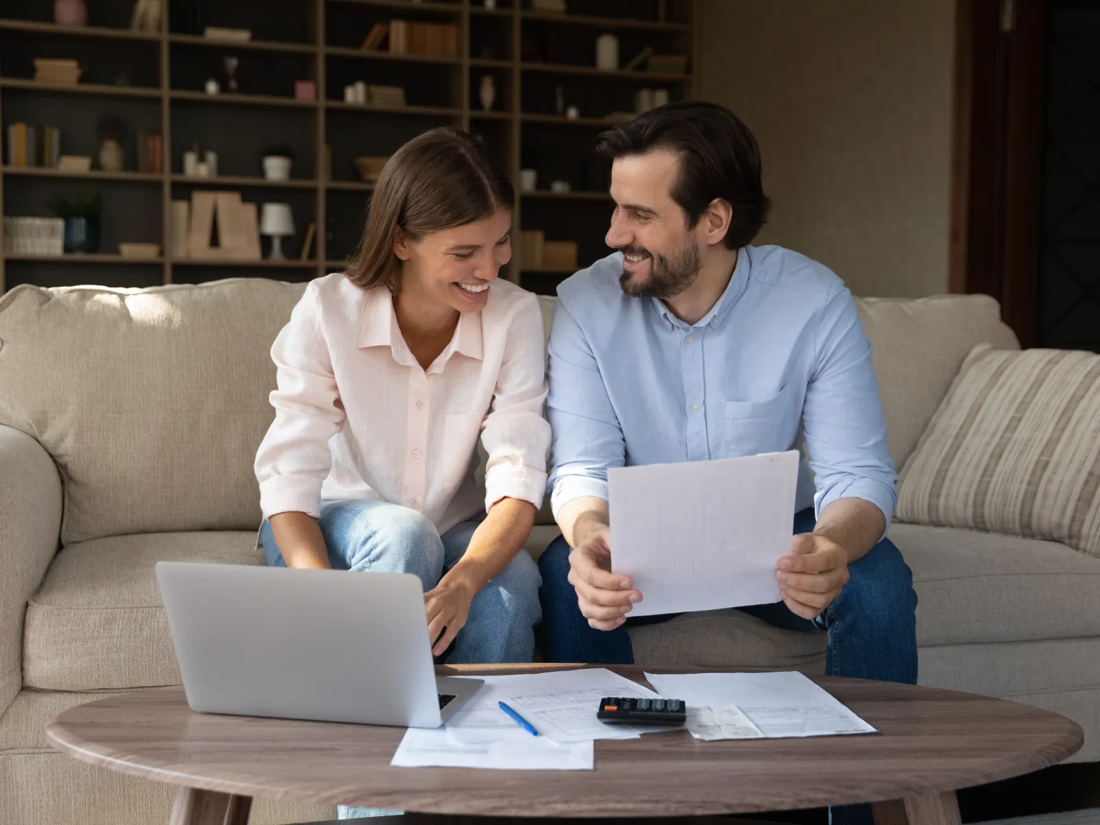 a man and a woman sitting on a couch looking at a laptop