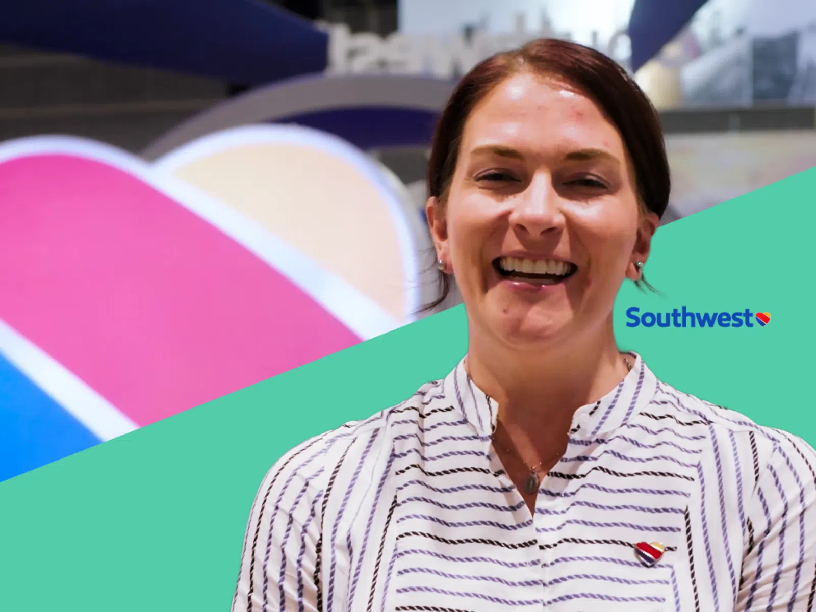Smiling woman wearing striped shirt with Southwest Airlines heart logo at an event with colorful background.