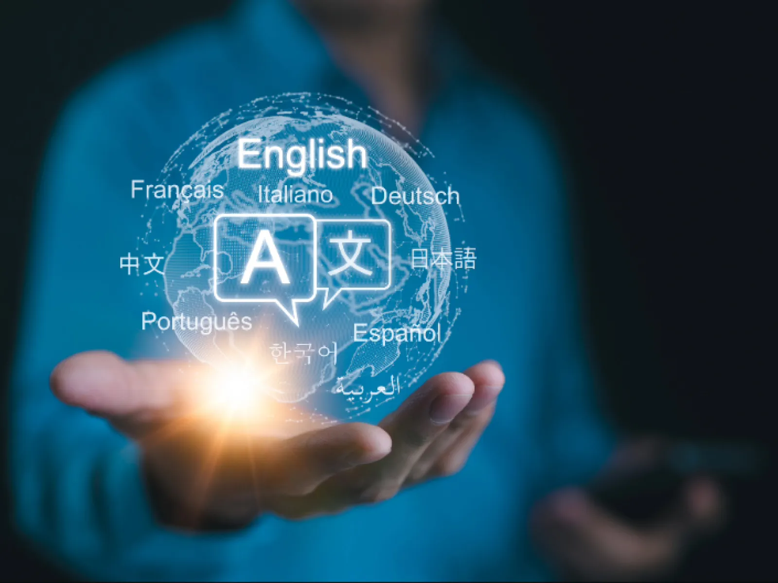 Hand holding glowing globe with multiple language names and translation icons representing global communication.