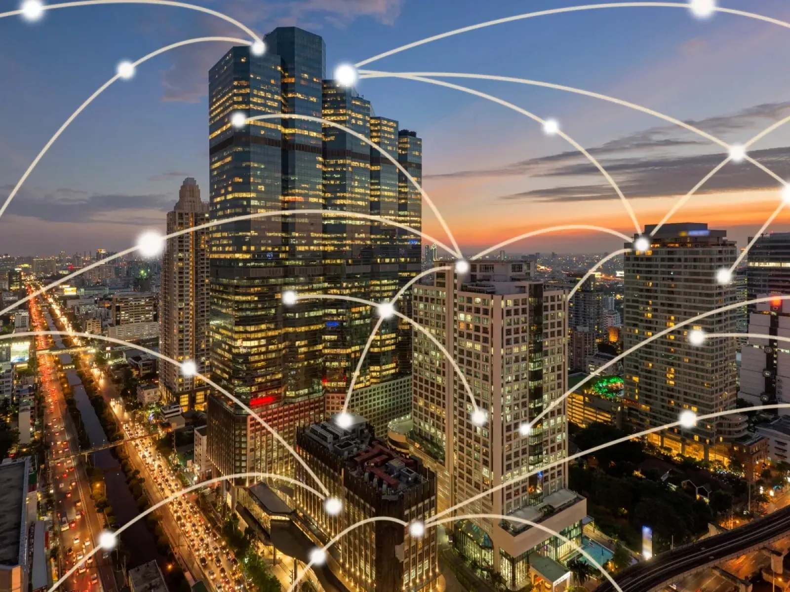 City skyline at dusk with illuminated buildings and digital network connection lines overlay