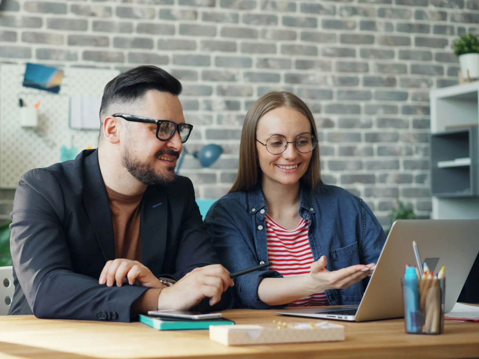 a man and a woman sitting at a table with a laptop