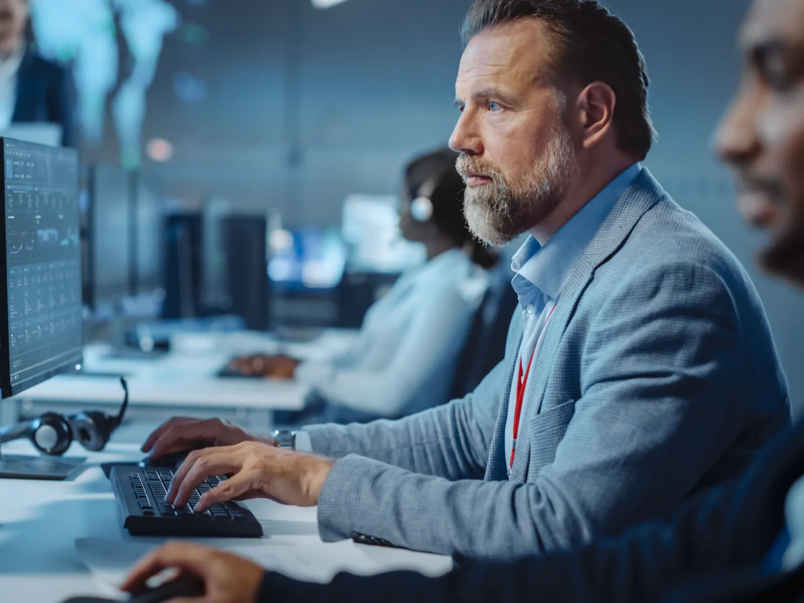 Focused male professional working on dual monitors with data analytics in modern office environment