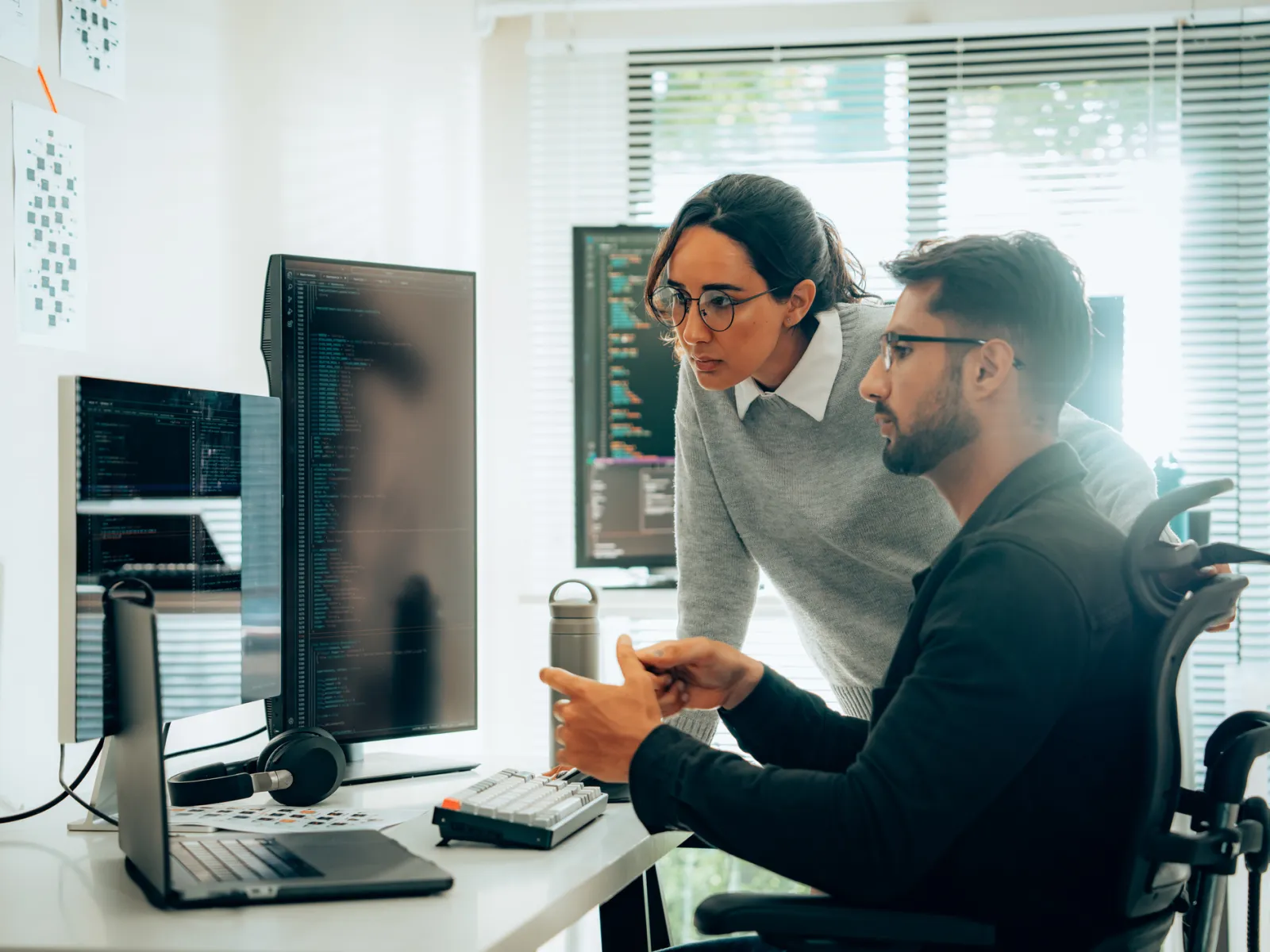 men sitting at a desk looking at a computer screen