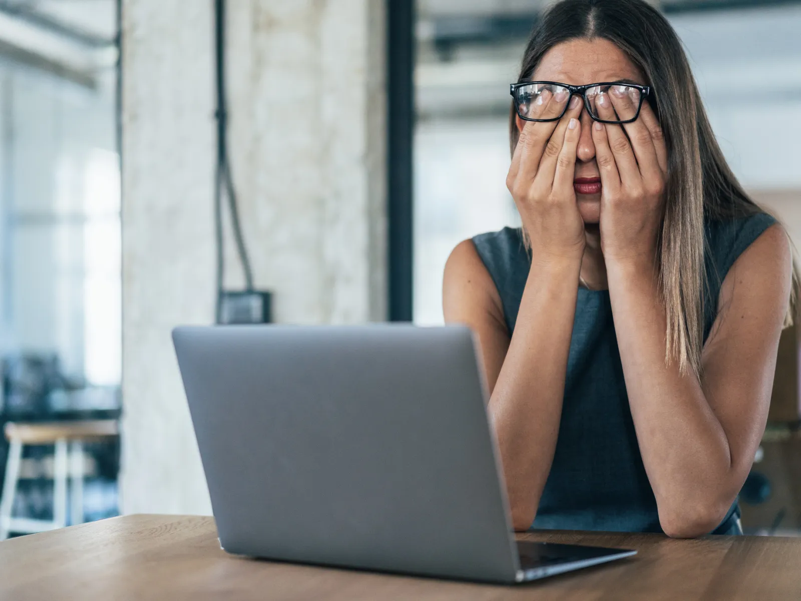 a woman with her hands on her face looking at a laptop
