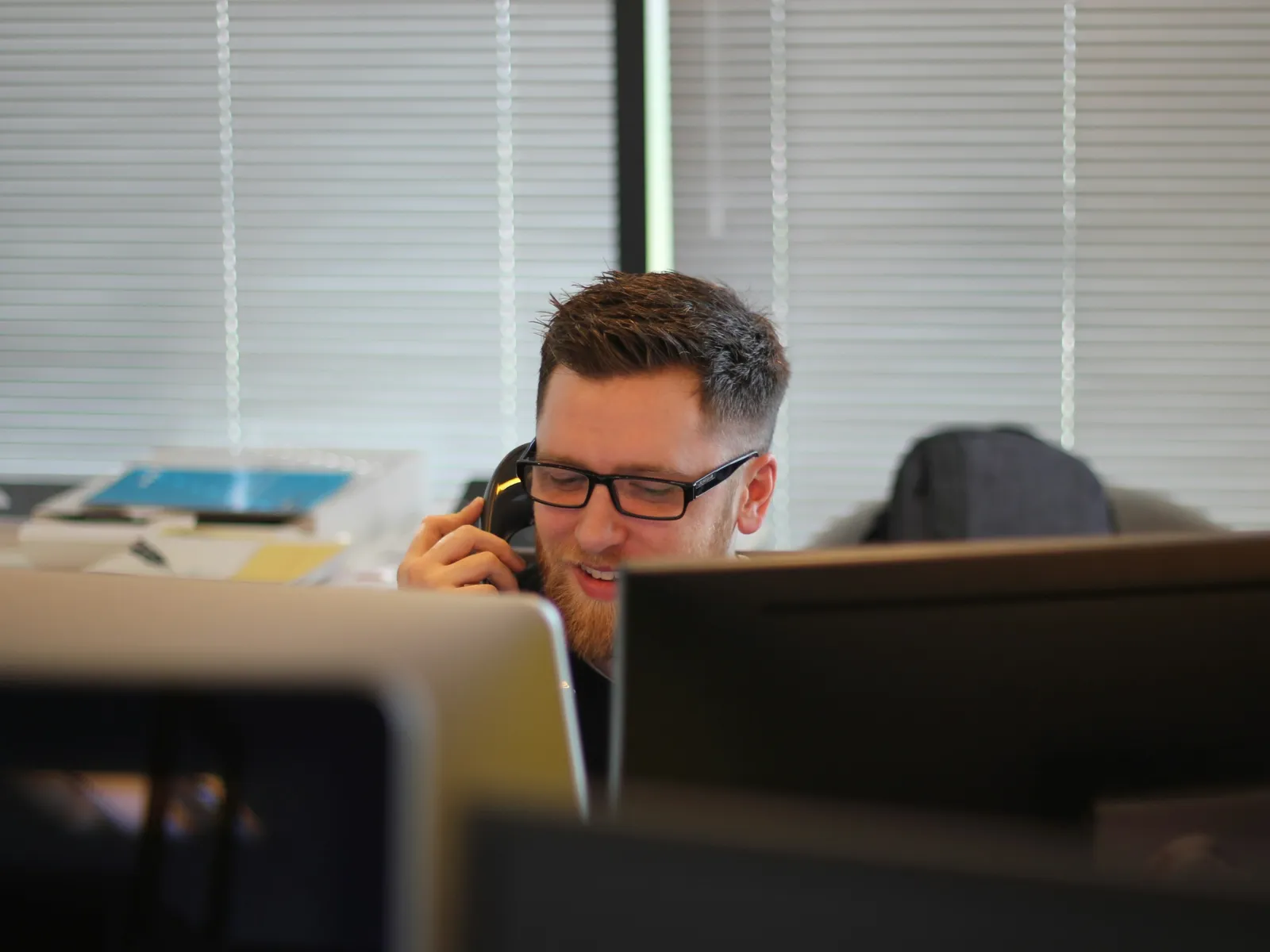 a man with a beard sitting at a desk with a computer