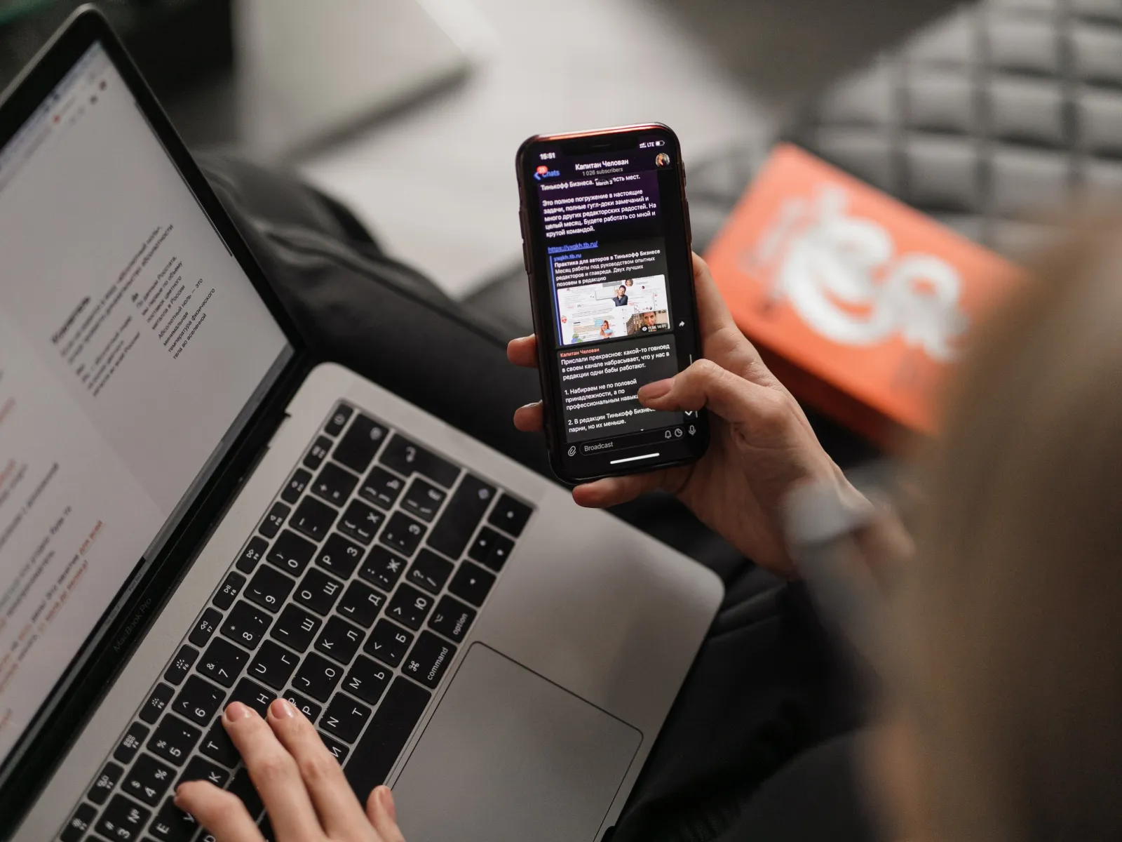 a hand holding a cellphone and a laptop