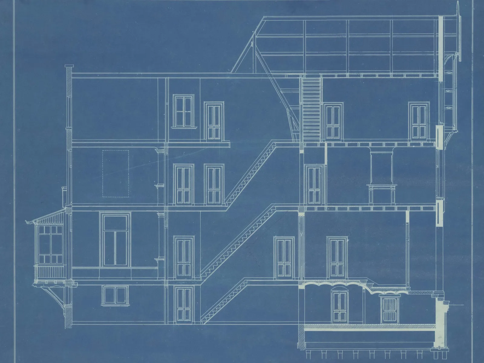 Detailed architectural blueprint showing a multi-story building's staircases, windows, and structural layout in white lines on blue background