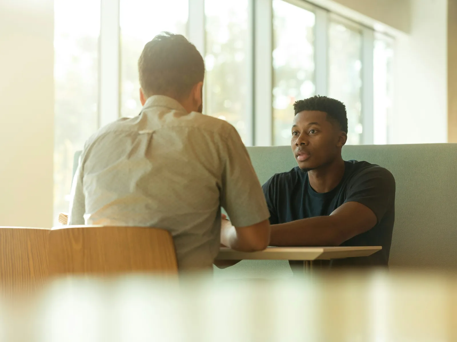 a man sitting at a desk looking at another man