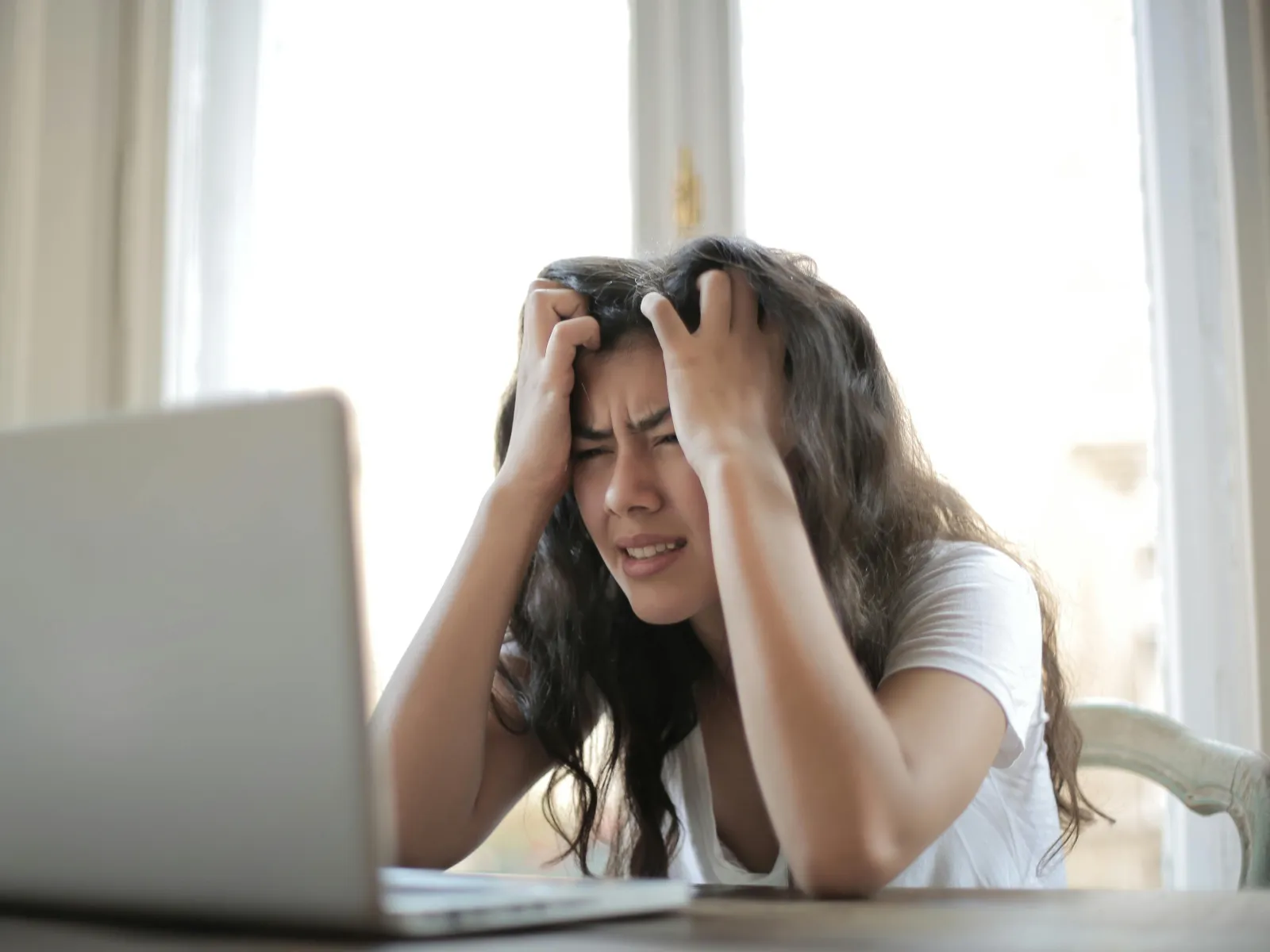 a woman with her head in her hands looking at a computer