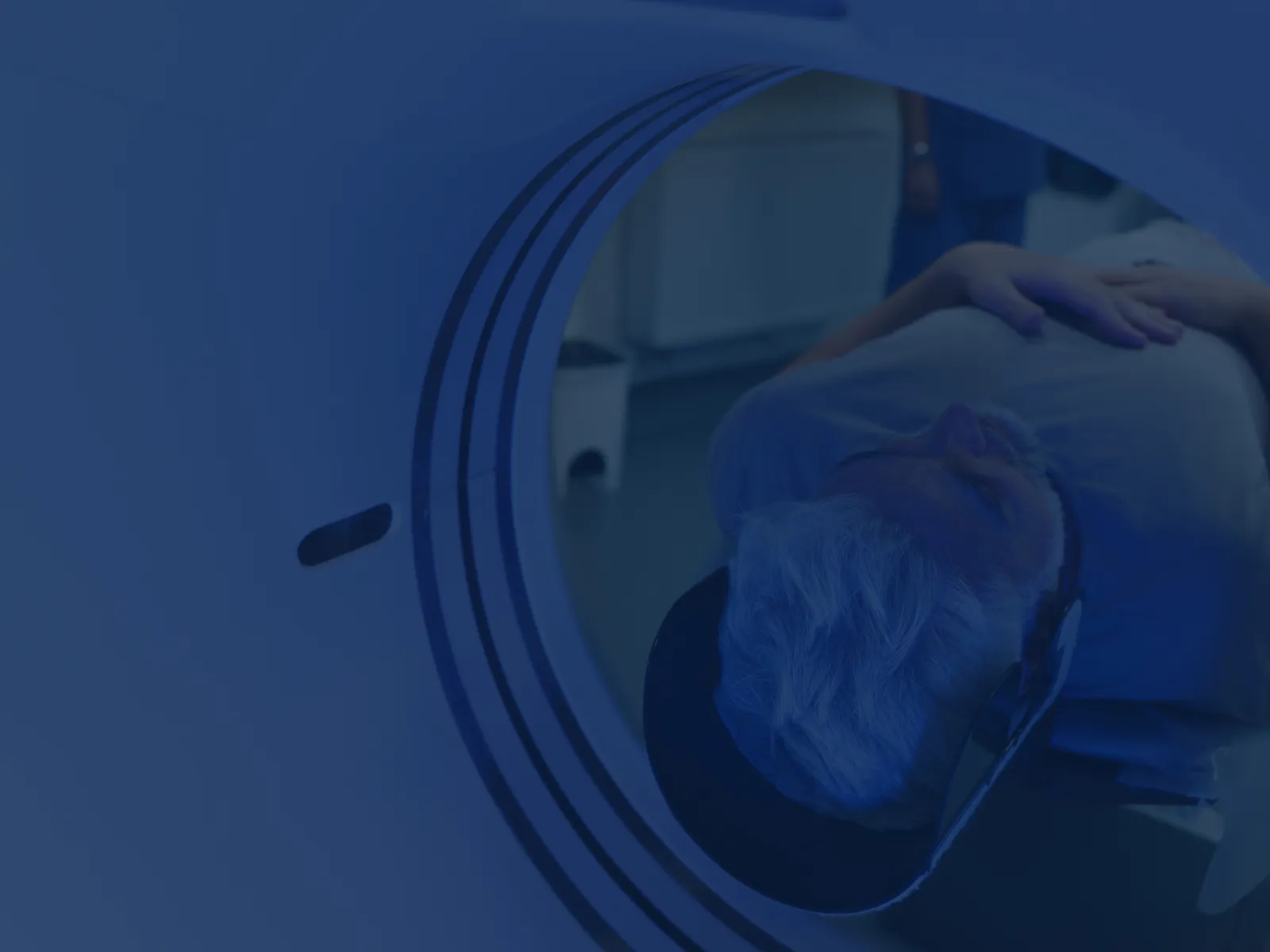 Elderly man undergoing a head MRI scan inside a medical imaging machine in a hospital setting.