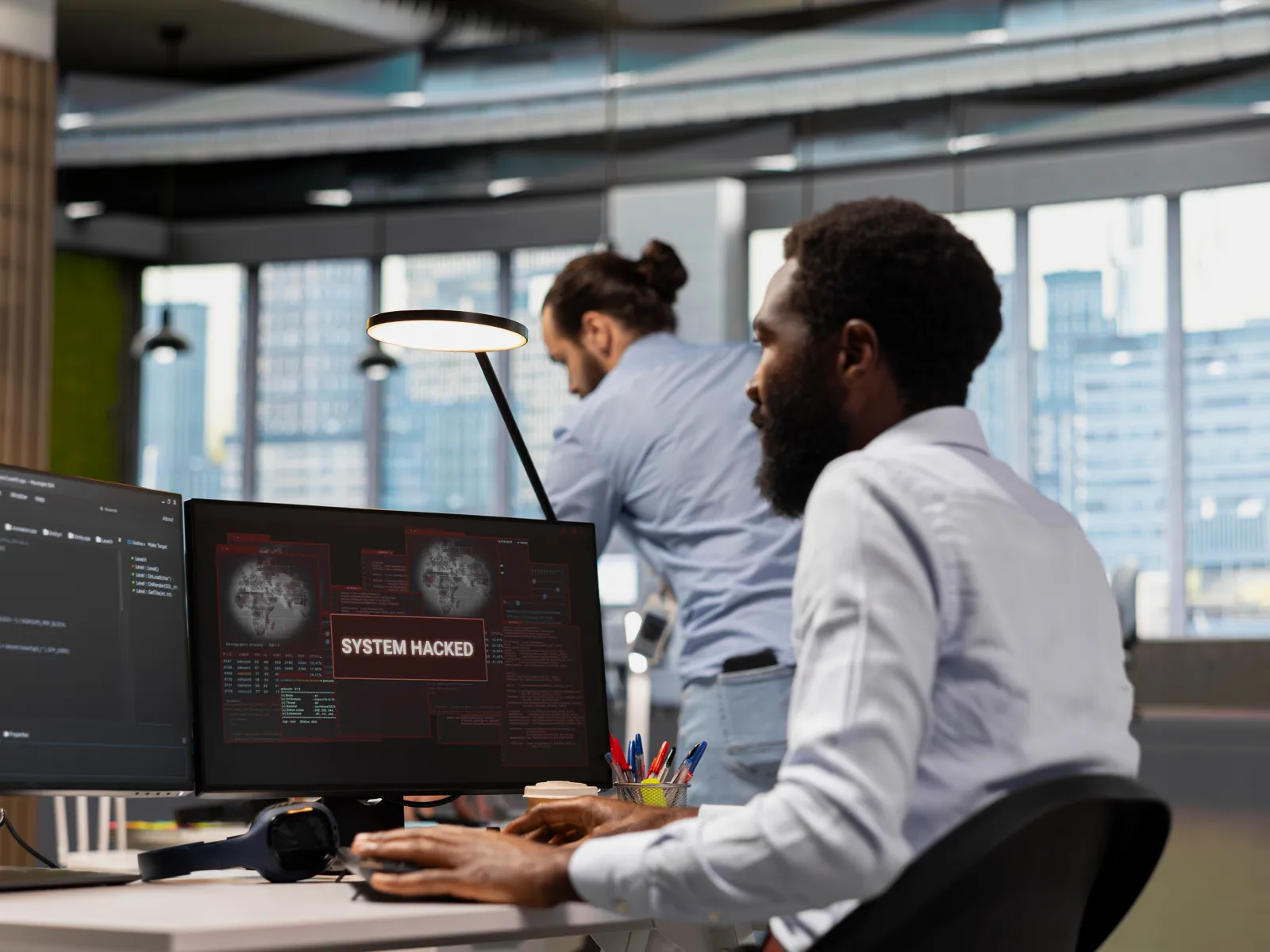 IT professional detects system hacked alert on computer screen in modern office environment.