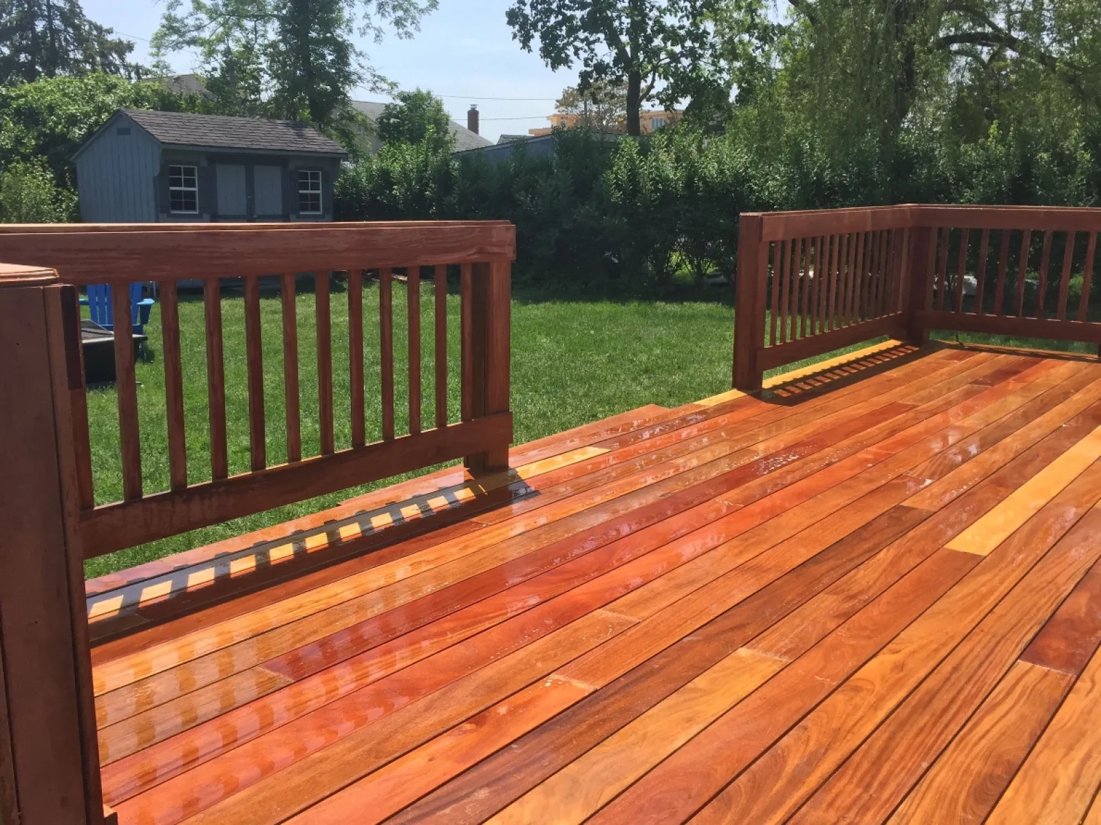 a deck with a wood railing and trees in the background