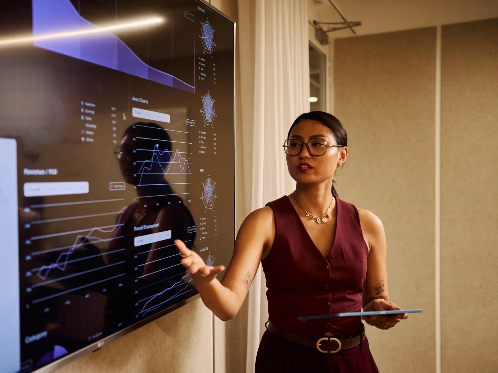 Businesswoman presenting data charts and graphs on a digital screen in a modern office setting.