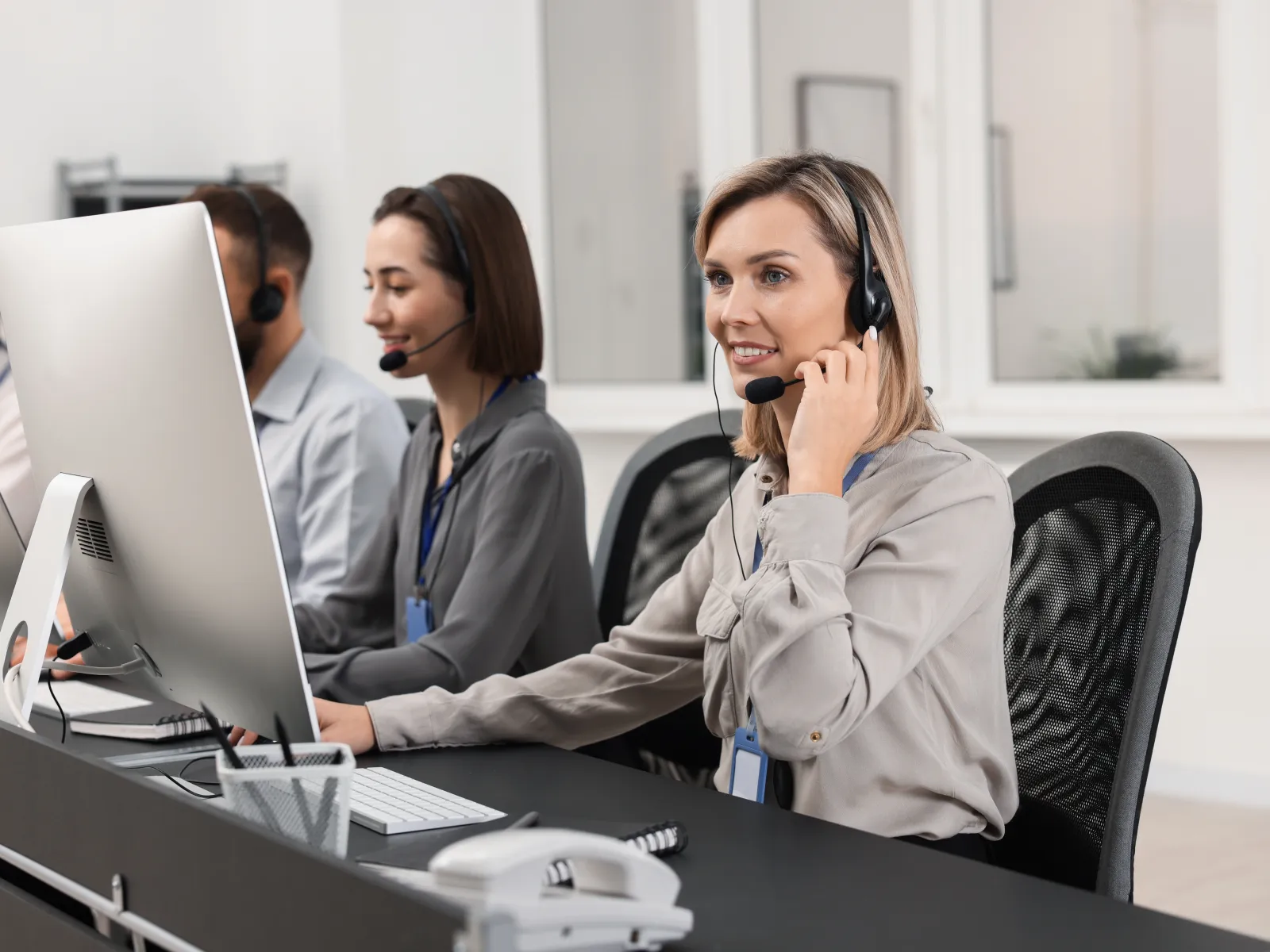 Customer service team working with headsets and computers in a modern office setting