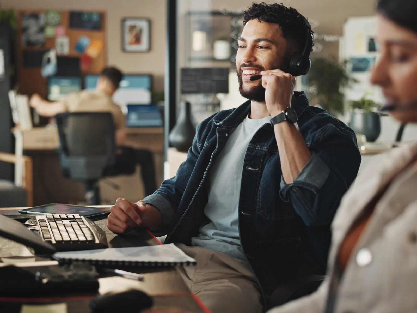 Customer service team working with headsets in modern office environment with computers and notebooks.