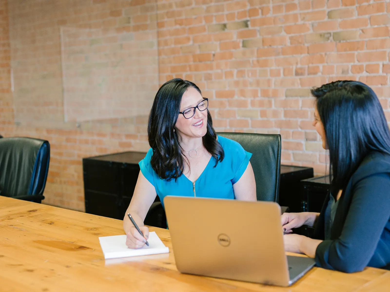 a couple of women sitting at a table looking at a laptop