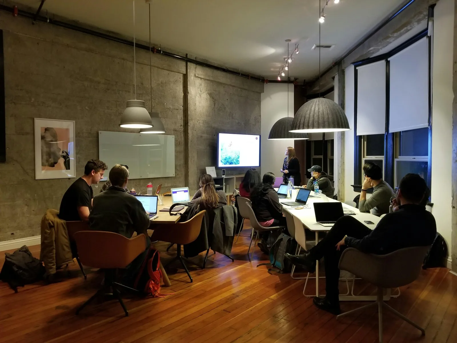 a group of people sitting around a table with laptops