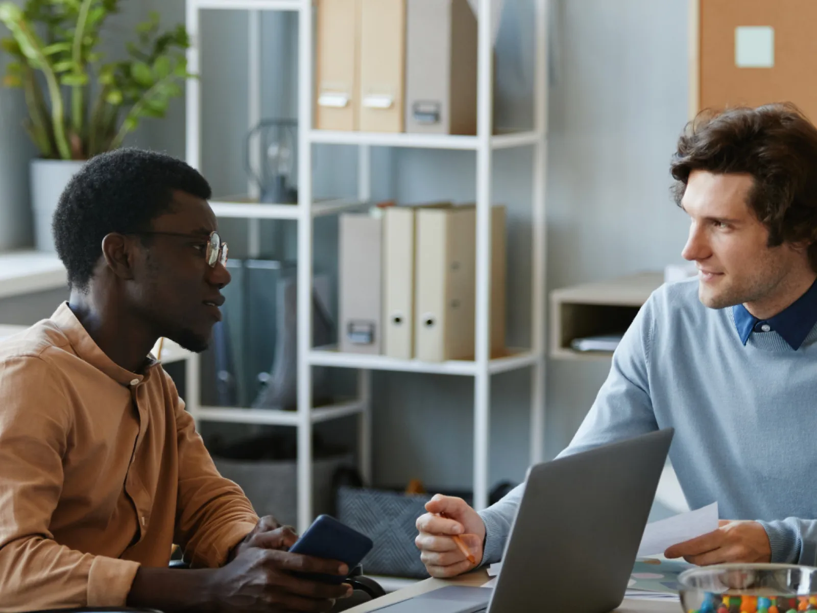 men sitting at a table looking at a laptop